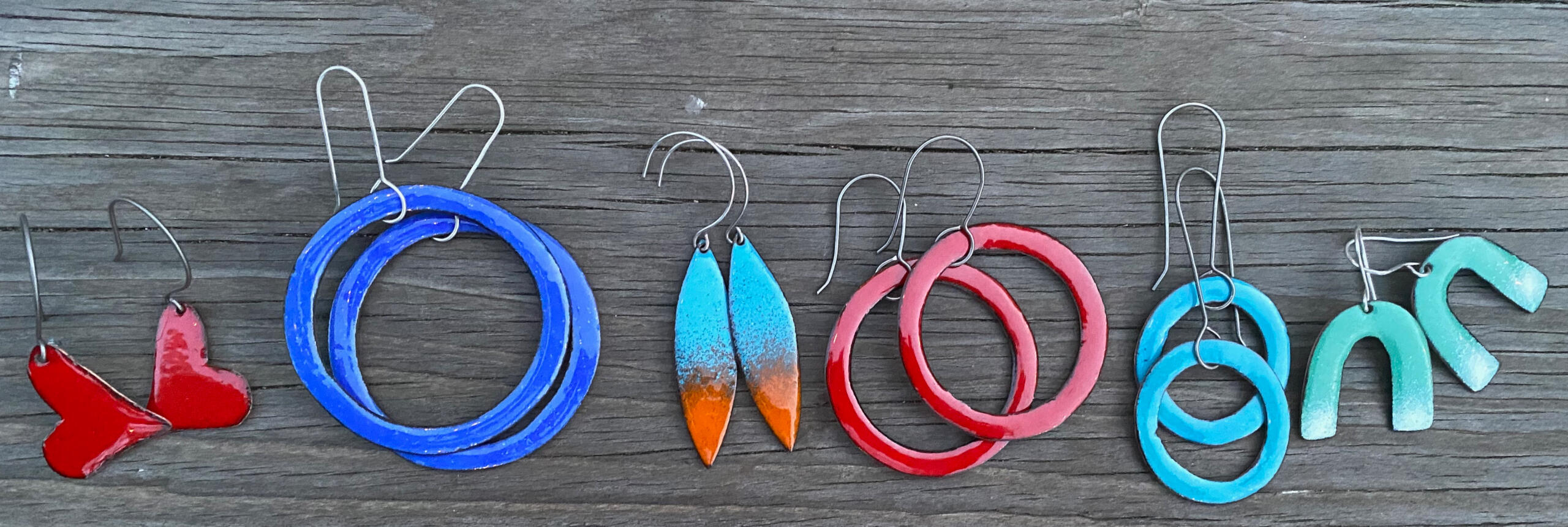 Handmade earrings, in bright turquoise, red, blue, orange and green kiln-fired glass enamel, are lightweight in modern hoop, heart and leaf shapes on recycled copper and titanium ear wire.
